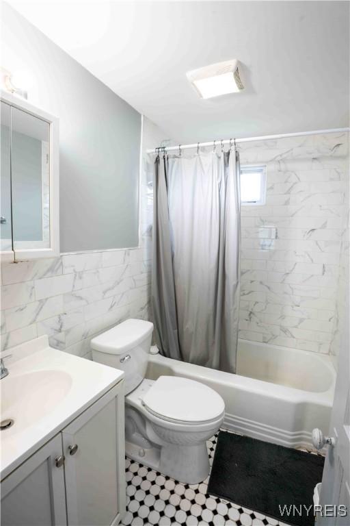 14 Phyllis Ave, Buffalo, NY 14215 - bathroom with vanity, shower / bath combination with curtain, wainscoting, tile patterned floors, and tile walls