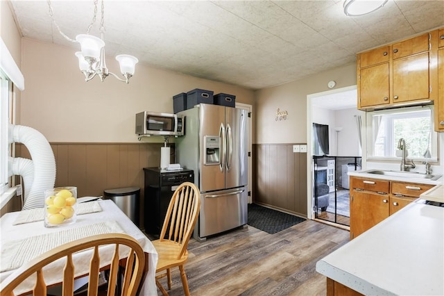 183 Castle Rd, Henrietta, NY 14623 - kitchen with appliances with stainless steel finishes, a wainscoted wall, light wood-style floors, light countertops, and a chandelier