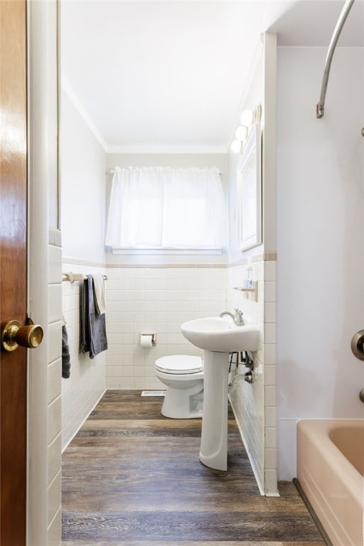 183 Castle Rd, Henrietta, NY 14623 - bathroom featuring tile walls, wood finished floors,  shower combination, crown molding, and a wainscoted wall