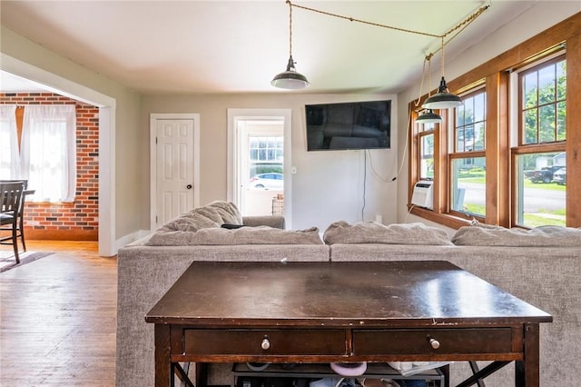 67 Pleasant St, Phelps, NY 14532 - living room featuring wood finished floors, healthy amount of natural light, brick wall, and cooling unit