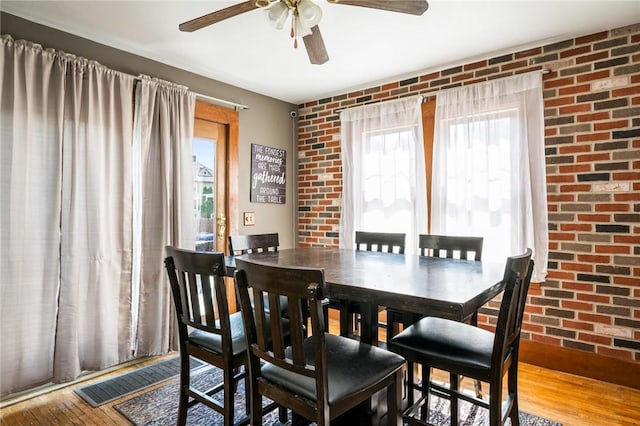 67 Pleasant St, Phelps, NY 14532 - dining space featuring ceiling fan, brick wall, and wood finished floors