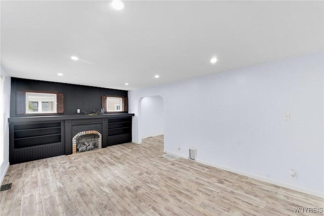 23 Lombardy St, Lancaster, NY 14086 - unfurnished living room featuring arched walkways, light wood-style flooring, a fireplace, and recessed lighting