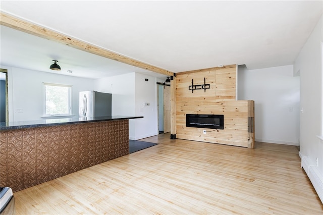 773 Marshall Rd, Chili, NY 14624 - unfurnished living room with wood finished floors, a barn door, a glass covered fireplace, and beamed ceiling
