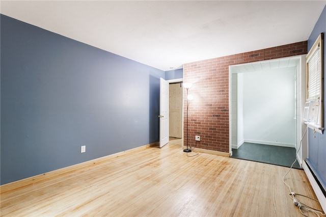 773 Marshall Rd, Chili, NY 14624 - unfurnished room with a baseboard heating unit, wood finished floors, and brick wall