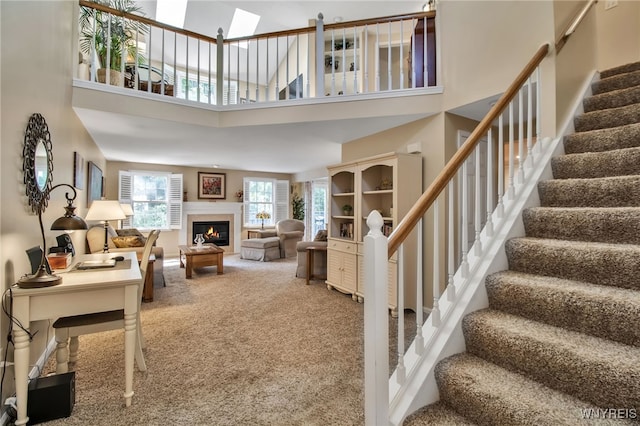 21 Towne Square Dr, Lancaster, NY 14086 - living area with a towering ceiling, carpet, stairway, a lit fireplace, and a skylight