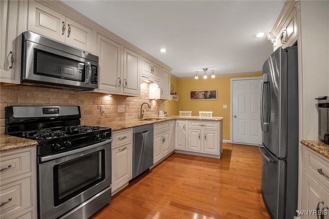 21 Towne Square Dr, Lancaster, NY 14086 - kitchen featuring appliances with stainless steel finishes, a peninsula, tasteful backsplash, light stone counters, and recessed lighting