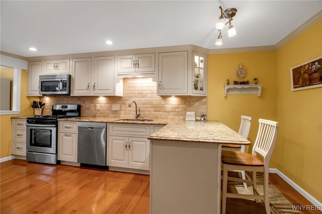 21 Towne Square Dr, Lancaster, NY 14086 - kitchen with stainless steel appliances, a peninsula, a breakfast bar, light wood-style flooring, and tasteful backsplash