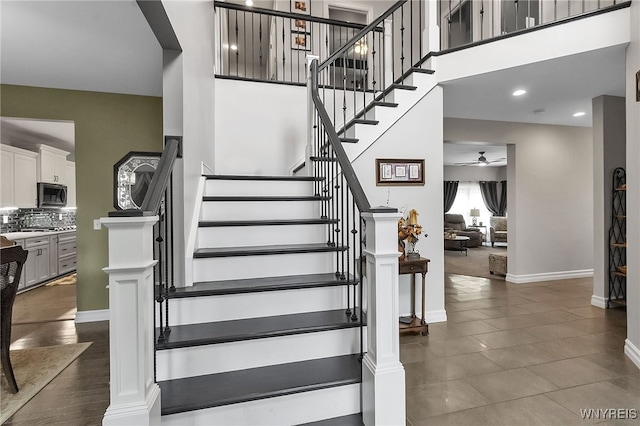 6132 Railroad St, Clarence, NY 14032 - stairway with a ceiling fan, a high ceiling, and tile patterned floors