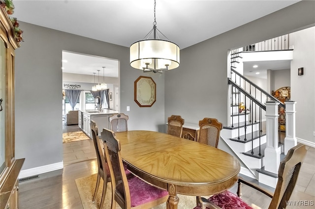 6132 Railroad St, Clarence, NY 14032 - dining room with wood finished floors, stairs, and a chandelier