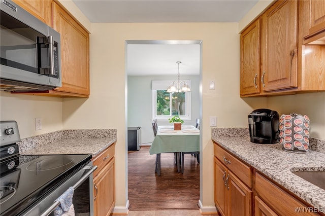 135 Charter Oaks Dr Unit 1, Amherst, NY 14228 - kitchen featuring stainless steel appliances, wood finished floors, a chandelier, and light stone countertops