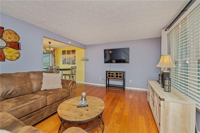 24 Huntsman, Webster, NY 14580 - living room with a chandelier, light wood-style flooring, healthy amount of natural light, and a textured ceiling