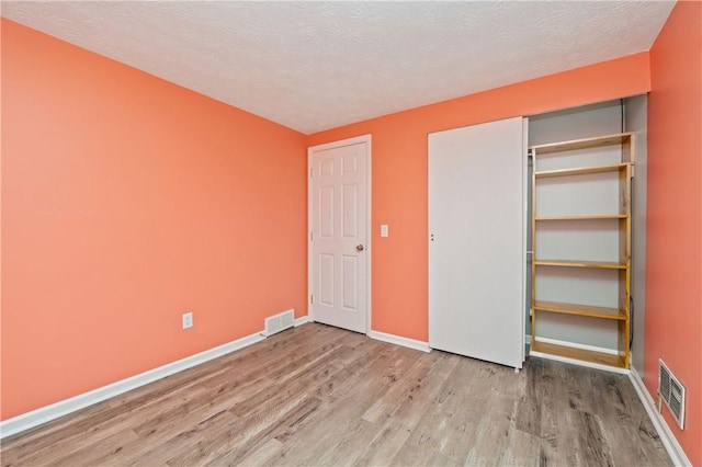 24 Huntsman, Webster, NY 14580 - unfurnished bedroom featuring wood finished floors, a textured ceiling, and a closet