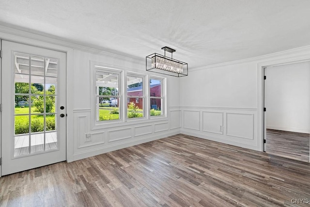 8953 Bushnell Shore Rd, Sullivan, NY 13037 - unfurnished dining area featuring plenty of natural light, a chandelier, a decorative wall, wood finished floors, and ornamental molding