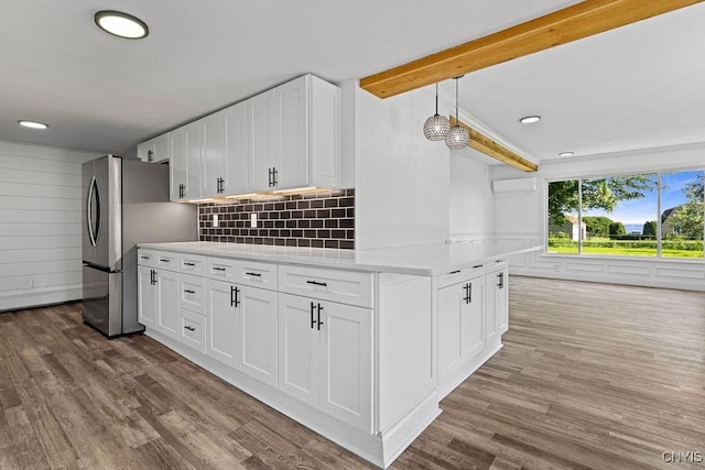 8953 Bushnell Shore Rd, Sullivan, NY 13037 - kitchen with beam ceiling, wood finished floors, light countertops, freestanding refrigerator, and white cabinetry