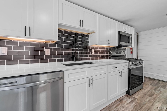 8953 Bushnell Shore Rd, Sullivan, NY 13037 - kitchen with stainless steel appliances, light wood finished floors, white cabinets, light countertops, and decorative backsplash