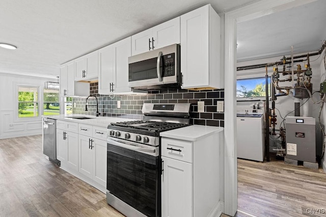 8953 Bushnell Shore Rd, Sullivan, NY 13037 - kitchen featuring appliances with stainless steel finishes, washer / clothes dryer, light wood finished floors, light countertops, and backsplash
