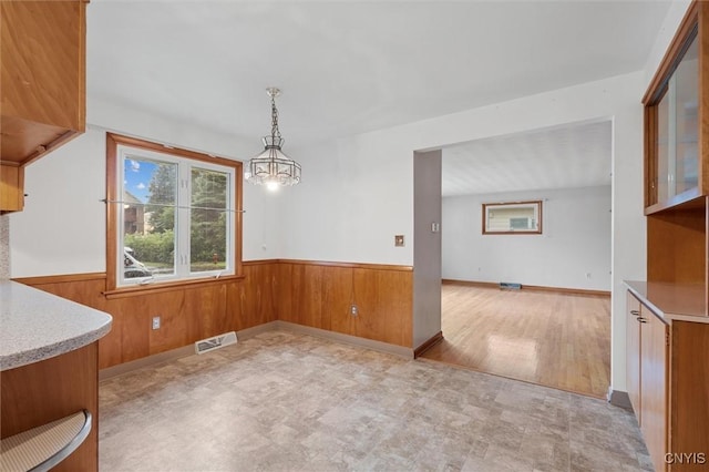 178 Wainwright Ave, Syracuse, NY 13208 - unfurnished dining area with a wainscoted wall, wooden walls, and a chandelier