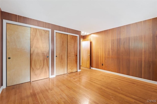 178 Wainwright Ave, Syracuse, NY 13208 - unfurnished bedroom featuring two closets, wood finished floors, and wood walls