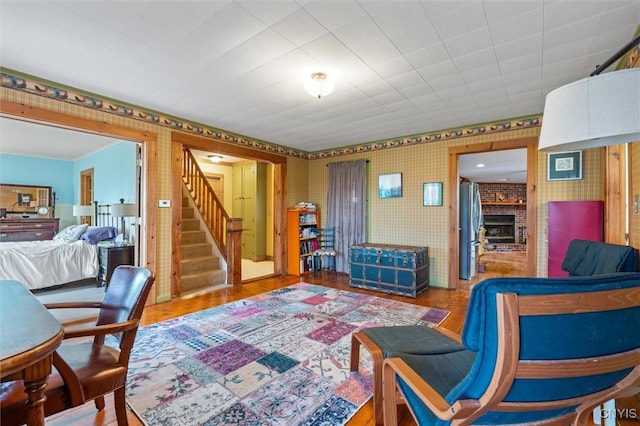 6767 Stauber Rd, Summerhill, NY 13073 - living room featuring wallpapered walls, wood finished floors, stairway, and a brick fireplace