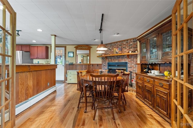 6767 Stauber Rd, Summerhill, NY 13073 - dining space featuring light wood finished floors, a fireplace, a baseboard radiator, wainscoting, and track lighting