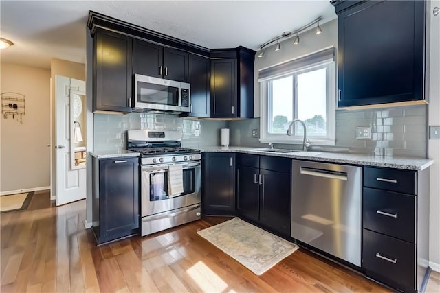 1125 Shoecraft Rd, Webster, NY 14580 - kitchen featuring appliances with stainless steel finishes, light wood-style flooring, light stone counters, and decorative backsplash