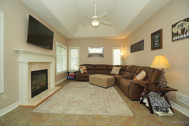 47 Timber Cove Ct, Amherst, NY 14051 - living room with a ceiling fan, a tiled fireplace, a raised ceiling, lofted ceiling, and stone finish floors