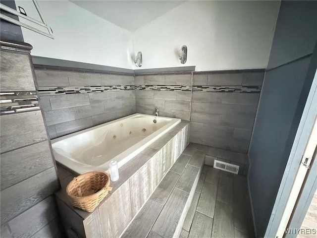7 High St, Lyons, NY 14489 - full bath featuring a whirlpool tub, tile walls, wood finish floors, and a wainscoted wall