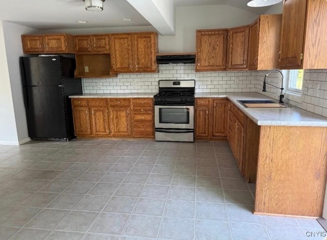 5709 Merry St, Verona, NY 13478 - kitchen with stainless steel gas stove, freestanding refrigerator, range hood, brown cabinetry, and decorative backsplash