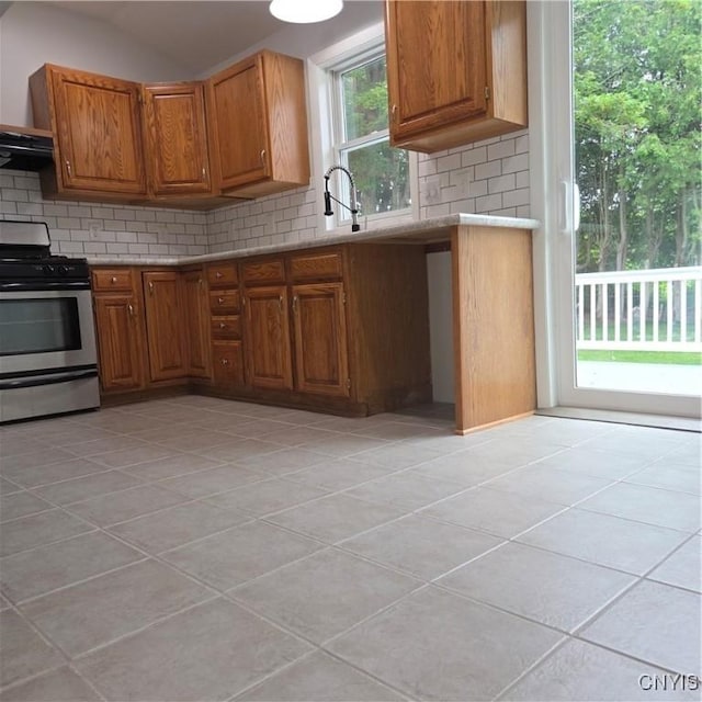5709 Merry St, Verona, NY 13478 - kitchen with stainless steel range with gas stovetop, backsplash, brown cabinets, light tile patterned floors, and lofted ceiling