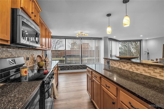 849 Delaware Ave Unit 404, Buffalo, NY 14209 - kitchen with electric range, stainless steel microwave, wood finished floors, tasteful backsplash, and a chandelier