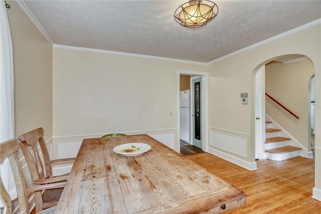 772 Winona Blvd, Irondequoit, NY 14617 - unfurnished dining area featuring arched walkways, wood finished floors, crown molding, and stairs