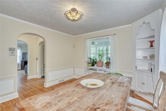 772 Winona Blvd, Irondequoit, NY 14617 - dining room with arched walkways, light wood finished floors, ornamental molding, and built in shelves