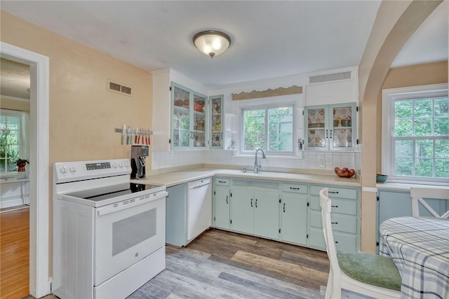 772 Winona Blvd, Irondequoit, NY 14617 - kitchen with white appliances, light wood-style flooring, backsplash, light countertops, and glass insert cabinets