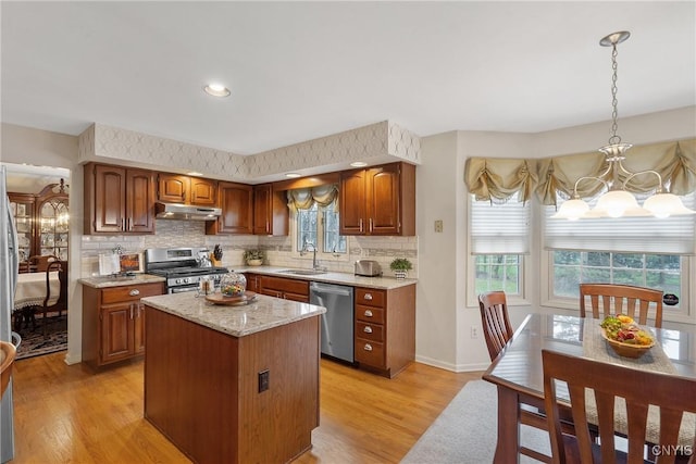 7619 Pico Ln, Lysander, NY 13027 - kitchen featuring stainless steel appliances, under cabinet range hood, a chandelier, light wood-style flooring, and decorative backsplash