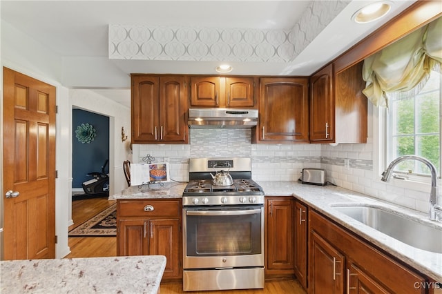 7619 Pico Ln, Lysander, NY 13027 - kitchen with stainless steel gas range, under cabinet range hood, light wood-style flooring, and light stone countertops
