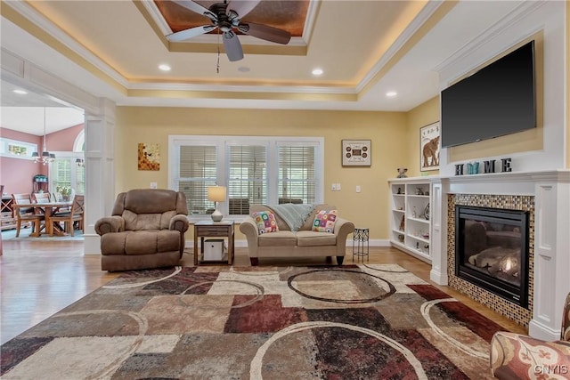 21 Donovan Dr, Oswego, NY 13126 - living area featuring a raised ceiling, a tile fireplace, a ceiling fan, wood finished floors, and crown molding