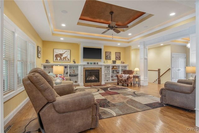 21 Donovan Dr, Oswego, NY 13126 - living room with a tray ceiling, crown molding, ceiling fan, wood finished floors, and a premium fireplace