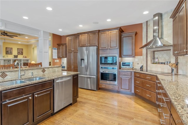 21 Donovan Dr, Oswego, NY 13126 - kitchen featuring stainless steel appliances, wall chimney exhaust hood, light wood-style flooring, decorative backsplash, and light stone countertops