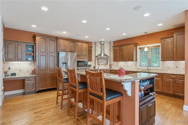 21 Donovan Dr, Oswego, NY 13126 - kitchen featuring stainless steel appliances, wall chimney range hood, backsplash, a kitchen breakfast bar, and light wood-style flooring