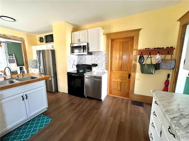 66 N Gordon St, Gouverneur, NY 13642 - kitchen with appliances with stainless steel finishes, dark wood-style floors, decorative backsplash, and white cabinetry