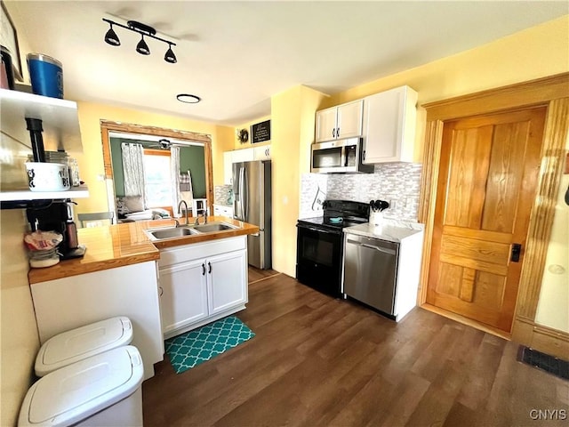 66 N Gordon St, Gouverneur, NY 13642 - kitchen featuring appliances with stainless steel finishes, white cabinetry, dark wood-style floors, and decorative backsplash