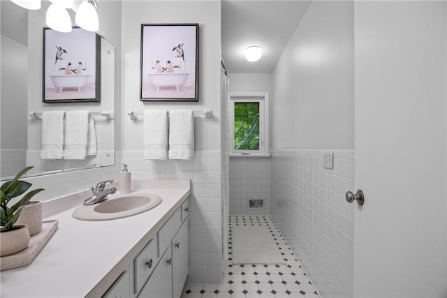 790 Oakridge Dr, Irondequoit, NY 14617 - bathroom featuring vanity, tile walls, a wainscoted wall, tile patterned flooring, and a shower