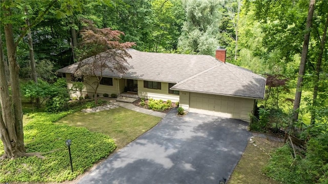 790 Oakridge Dr, Irondequoit, NY 14617 - single story home with asphalt driveway, a chimney, an attached garage, roof with shingles, and a forest view