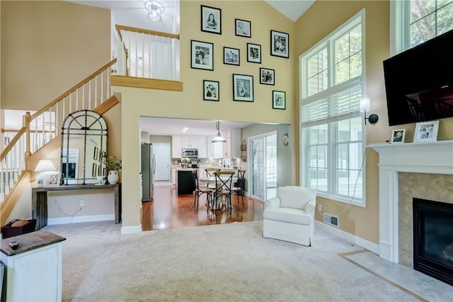 906 Lothario Cir, Webster, NY 14580 - carpeted living room featuring high vaulted ceiling, stairway, and a fireplace with flush hearth