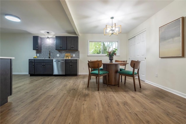 23 Kerry Park, Henrietta, NY 14534 - kitchen with stainless steel dishwasher, a chandelier, wood finished floors, decorative backsplash, and light countertops