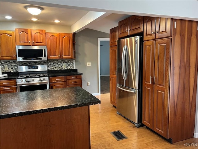 19 Beech Dr, Scriba, NY 13126 - kitchen featuring appliances with stainless steel finishes, light wood-style flooring, backsplash, dark countertops, and brown cabinetry