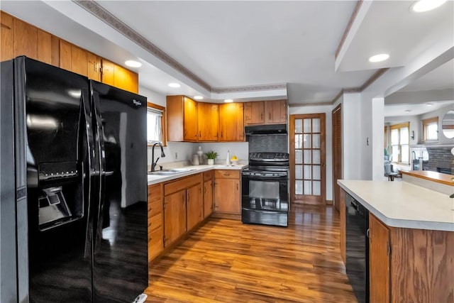 128 Princeton Blvd, Tonawanda, NY 14217 - kitchen with black appliances, under cabinet range hood, light wood-type flooring, light countertops, and brown cabinets