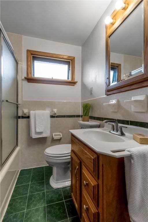 128 Princeton Blvd, Tonawanda, NY 14217 - full bathroom featuring vanity, tile walls, tile patterned flooring, shower / bath combination with glass door, and a wainscoted wall