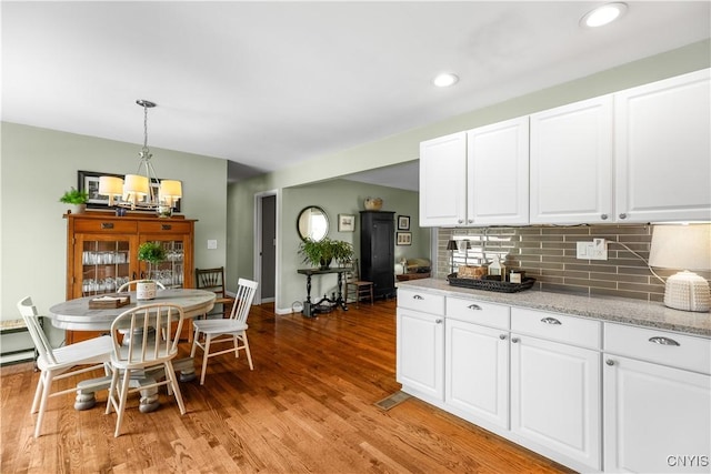 102 W Rand St, German Flatts, NY 13357 - kitchen featuring a chandelier, light wood-type flooring, tasteful backsplash, white cabinetry, and hanging light fixtures