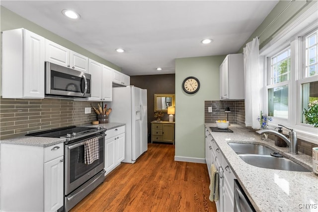 102 W Rand St, German Flatts, NY 13357 - kitchen featuring appliances with stainless steel finishes, wood finished floors, light stone counters, white cabinets, and decorative backsplash